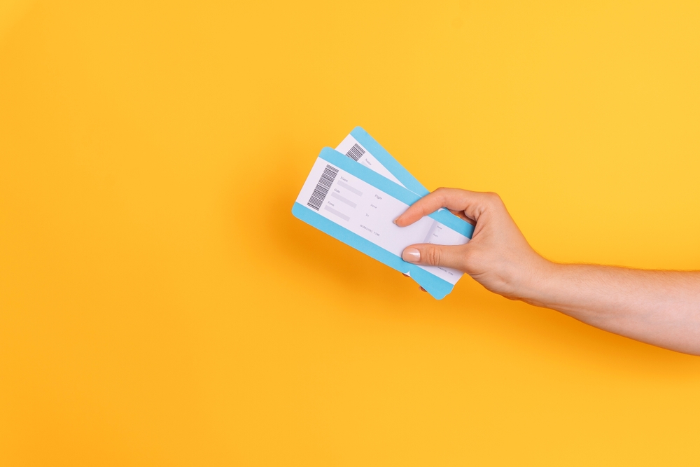 Hand,Holding,Tickets,Against,Yellow,Background.